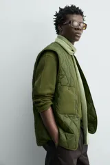 Parka técnica color verde militar de corte relaxed fit con cuello subido y capucha desmontable. Cuenta con bolsillos con solapa en el pecho y en la cadera, cintura ajustable con cordón y cierre frontal de cremallera oculta por solapa con botones a presión. Incluye un chaleco interior desmontable acolchado.
