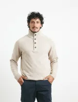 Sweater de punto color azul marino, con cuello alto, cierre frontal parcial y tapeta con botones. Presenta mangas raglán y puños y ruedo acanalados.