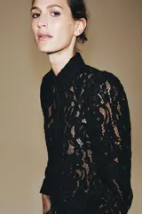 Blazer de encaje negro con hilatura de algodón, cuello redondo, manga larga y cierre frontal de botones.