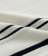 Camisa polo de punto color crema con rayas verticales azul marino, cierre de cremallera, cuello polo y mangas cortas con ribete a juego. Corte slim fit.