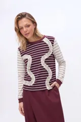 Remera manga larga de viscosa con rayas horizontales en color bordó y blanco, destacada por volados ondulados decorativos en el frente.