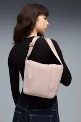 Cartera tipo bucket bag de la marca Puma, color rosado con textura sutil arrugada, diseño estructurado, correa ajustable para el hombro y el logo del felino en metal dorado.