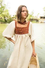 Túnica de lino color crudo con corte holgado y mangas abullonadas con elástico. Presenta una pechera frontal y trasera con estampado étnico en tonos terracota y amarillo.