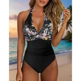 Malla entera de color verde oscuro, combinada con un diseño floreado en la parte inferior. Presenta escote halter cruzado y fruncidos en la zona del abdomen.