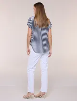 Camisa de calce holgado color blanco con rayas verticales negras, cuello camisero clásico, abotonadura frontal y mangas cortas.