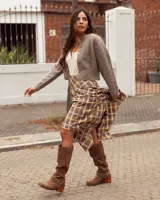 Botas de caña alta confeccionadas en cuero gamuzado color marrón. Presentan un diseño de estilo western con puntera cuadrada, taco de madera y una tira decorativa con estribo metálico desmontable en la zona del tobillo.