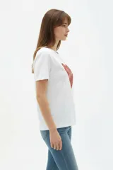 Remera de algodón blanca, de corte holgado, con cuello redondo y diseño estampado en el centro que incluye un gato comiendo de un plato y la inscripción 'Wild Cats'.