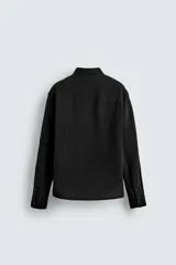 Camisa de corte regular fit confeccionada en tejido de algodón con textura de cuadrillé. Presenta cuello solapa, manga larga con puños abotonados y cierre frontal mediante botonadura.