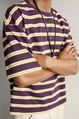Camiseta de corte relaxed fit con diseño de rayas horizontales en tonos morado, amarillo y blanco. Presenta cuello redondo y mangas cortas.