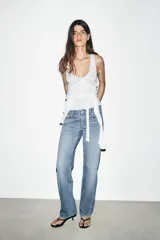 Jeans de tiro bajo con corte recto, confeccionados en denim negro con efecto lavado. Presentan cinco bolsillos, trabillas para cinturón y cierre frontal con cremallera y botón metálico.