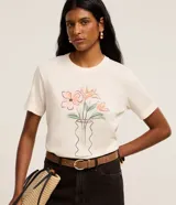 Remera Marfinno de corte regular, confeccionada en mezcla de poliéster, algodón y lino, color crudo con fondo melange. Presenta cuello redondo, mangas cortas y estampa frontal de un florero con flores.