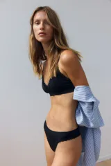 Soutien sin aros color negro, con diseño seamless, copas con relleno extraíble y detalle de encaje en los bordes. Cuenta con doble tirante ajustable en cada hombro.