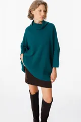 Sweater de tejido de punto suave en color beige, con silueta holgada, cuello alto y mangas tres cuartos con puños definidos.