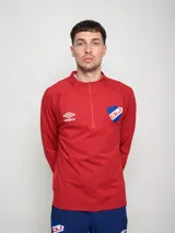 Buzo deportivo de polytraining color rojo, con medio cierre frontal y cuello alto. Presenta el logo de Umbro en el pecho izquierdo y el escudo del Club Nacional de Football en el pecho derecho.