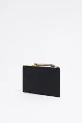 Cartera negra de estructura blanda con cierre de cremallera y tirador de cordón. Presenta logo metálico dorado "BIMBA Y LOLA" en el frente, acabados metálicos dorados y tarjetero interior.