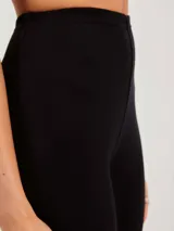 Calza larga negra de tejido de punto, con puño en los tobillos.