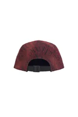 Gorra tipo camp cap de Supreme, confeccionada en denim con efecto lavado y estampado de estilo gótico en toda la superficie. Presenta el logo de la marca en un parche rectangular frontal y ojales laterales para ventilación.