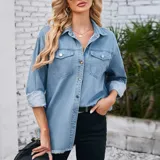 Campera tipo sobrecamisa de denim en tono azul claro, con corte oversize, cuello italiano, cierre frontal con botones metálicos, bolsillos frontales con solapa y ruedo con detalle desflecado.