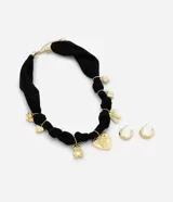 Conjunto compuesto por un collar de tela negra con nudos y dijes metálicos dorados (corazón, osito, lazo, candado) y un par de aros tipo argolla dorados.