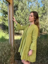 Vestido amplio de lino color verde lima, con cuello mao y abertura frontal con botones de coco. Presenta un diseño con canesú fruncido y volados en los puños de las mangas largas.