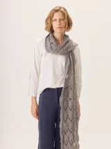 Bufanda larga tejida a dos tonos, gris azulado y beige, con diseño calado de rombos y bordes ondulados.