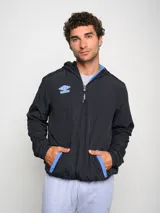 Canguro negro con capucha y medio cierre, marca Umbro, modelo Urban. Detalles en azul en el logo, interior de la capucha y ribete de los bolsillos.