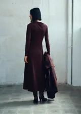 Vestido midi de corte evasé color marrón, confeccionado en tejido elástico, con cuello asimétrico y manga larga.