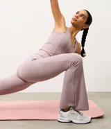 Pantalón deportivo Get Over modelo flare, confeccionado en microfibra acanalada de color lila. Presenta un corte ajustado en caderas y muslos con apertura acampanada desde la rodilla.