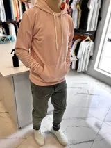 Canguro de felpa color rosado, con capucha ajustable mediante cordones blancos, bolsillo tipo canguro frontal y pequeño logo bordado en el pecho.
