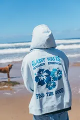 Hoodie de color celeste con capucha, confeccionado en tejido de algodón. Presenta un diseño bordado en la espalda con motivos florales y texto en tonos azules.