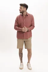 Camisa de manga larga con cuello clásico y cierre frontal de botones. Presenta un diseño de corte regular en color salmón.