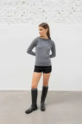 Botas de caña media confeccionadas en cuero vacuno, con diseño de punta redondeada y suela plana con pequeño taco cuadrado. Presentan costuras verticales decorativas a lo largo de la caña.