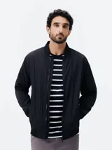 Campera bomber negra con cierre frontal, cuello, puños y dobladillo en rib elástico, y bolsillos laterales.