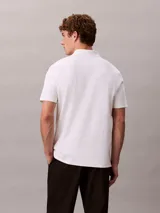 Chomba de manga corta Calvin Klein confeccionada en algodón interlock, con cuello clásico y cierre frontal de botones.
