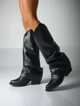 Bota de caña alta color negro, de cuero sintético, con punta cuadrada y efecto arrugado en el tobillo.