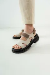Sandalias de cuero marrón con diseño de tiras anchas y ajuste mediante velcro. Presentan una plantilla acolchada color tostado con detalles en rojo y una suela de goma negra con plataforma dentada.
