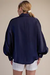 Blusa de satén azul marino con cuello camisero y mangas largas voluminosas con puños abotonados.
