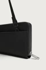 Cartera tipo bandolera de acabado engomado en color negro, con bolsillo frontal con cremallera y compartimento principal con cierre. Asa de hombro ajustable y extraíble.