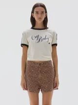 Short tiro alto color marrón con estampado de cuadros en tonos beige y azul oscuro. Presenta cortes verticales en la parte delantera y desgaste en las costuras.