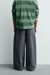 Pantalón wide fit color gris oscuro, confeccionado en tejido ligero de algodón. Cuenta con cinco bolsillos y efecto lavado. Cierre frontal con cremallera y botón.