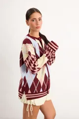 Saco liviano oversize de punto con diseño de rombos argyle y flores celestes sobre fondo marrón, rojo y crema, con cierre frontal de botones y cuello redondo.