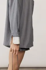 Camisa oversize a rayas color verde menta con cuello y puños en contraste de color blanco. Presenta cierre frontal con botones y un bolsillo aplicado en el pecho.