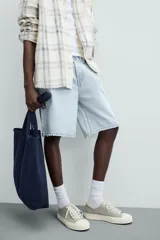 Bermuda de denim de algodón, color verde claro lavado, de corte recto y tiro medio. Presenta cinco bolsillos y cierre frontal con cremallera y botón.