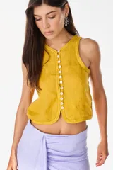 Top musculosa amarillo de lino italiano, con cuello redondo y cierre frontal de botones de nácar.