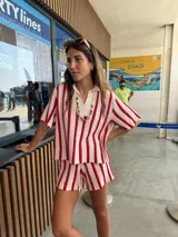 Blusa tipo polo de tejido de punto con diseño de rayas verticales en color rojo y blanco, cuello en V y mangas cortas holgadas.