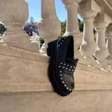 Mocasines de cuero negro con plataforma y suela de goma, decorados con tachas metálicas plateadas en el empeine y el talón.