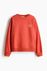 Buzo oversized de cuello redondo y manga larga, en color coral, con el texto 'L'AMOUR PARIS' bordado en el pecho en color blanco.