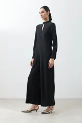 Mono largo negro con textura amasada, cuello mao con abertura en forma de gota, mangas largas y cinturón plateado de eslabones.