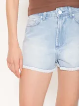 Short de jean celeste de tiro medio, corte clásico y calce relajado. Tiene roturas y ruedo desflecado.