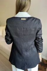 Blazer azul de lino con corte entallado, cuello y solapas combinadas en color gris, cierre con botón de nácar, bolsillos laterales y tajo en la espalda.